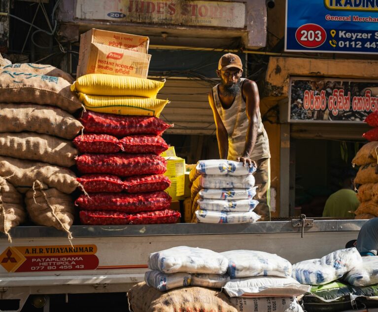 Worker loading sacks onto a truck, the kind of work manpower services for rice mills support